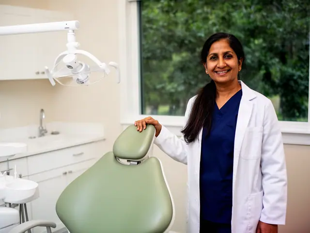 Smiling dentist in a white coat resting her hand on a new sage-green dental chair in her practice