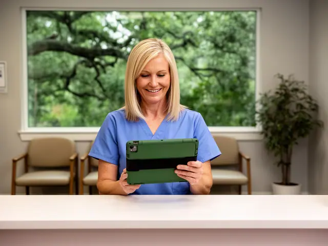 Smiling clinic office manager in blue scrubs reviewing a tablet at a white reception counter